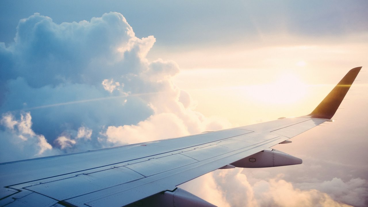 Flygplansvinge ovan molnen i varmt ljus